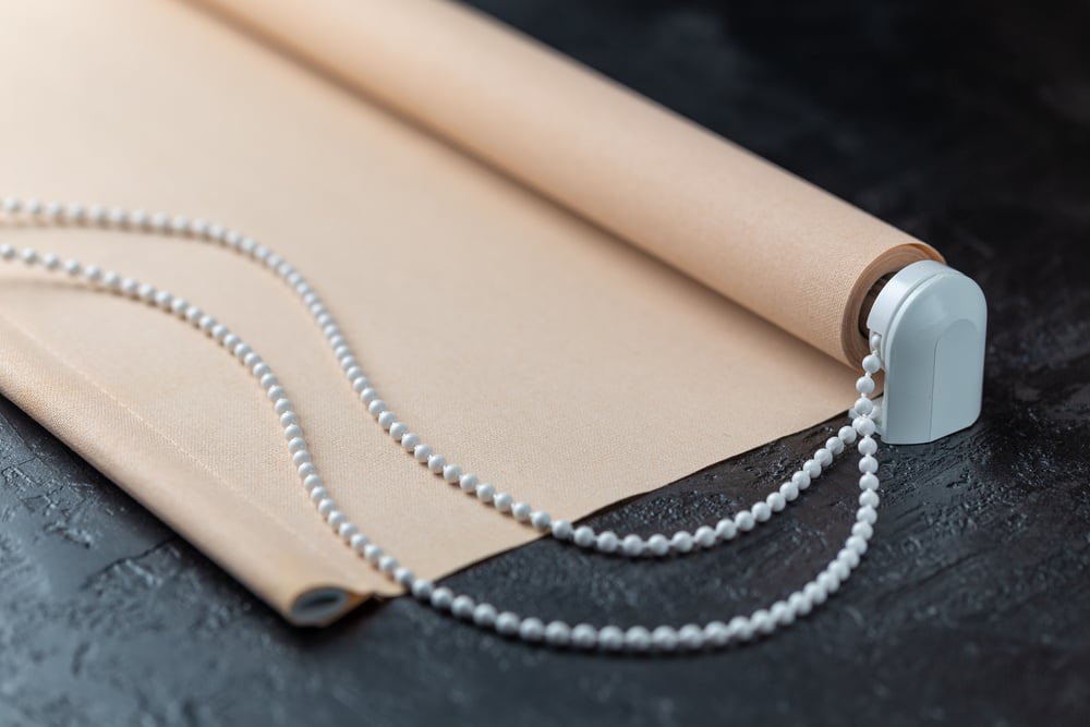 The roller blind lies on a black stone surface.